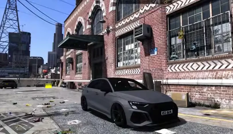 In a screenshot of the game, GTA Mzansi Kasi Vibes LGSA, a matte black car parked outside a brick warehouse in an urban environment, with debris scattered on the ground.